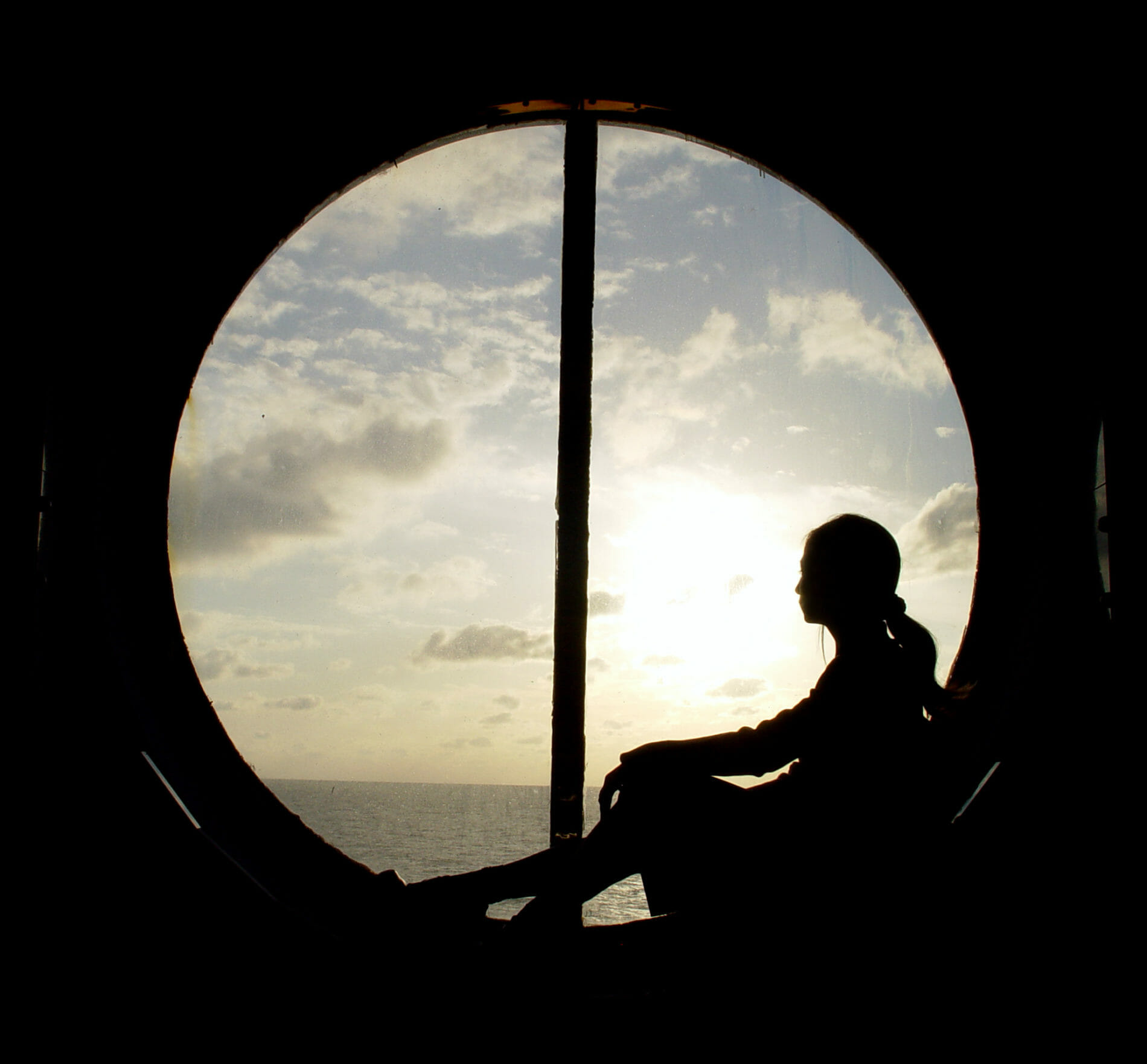 Silhouette of Woman Sitting in Ship's Porthole Window